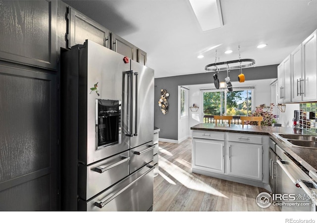 kitchen featuring sink, white cabinetry, appliances with stainless steel finishes, kitchen peninsula, and light hardwood / wood-style floors