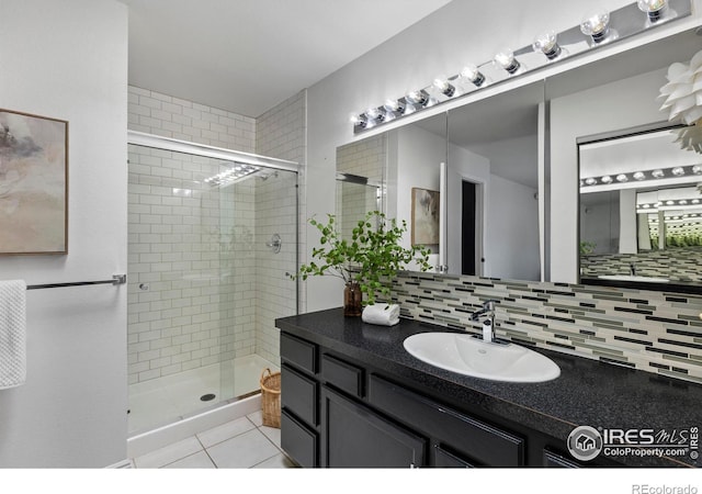 bathroom with tile patterned floors, a shower with door, vanity, and backsplash