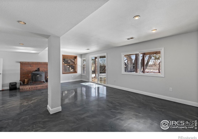 unfurnished living room featuring a wood stove and a textured ceiling