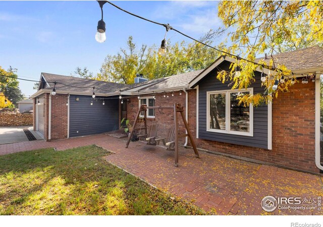 rear view of house featuring a garage, a lawn, and a patio