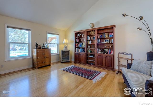 sitting room with lofted ceiling, beverage cooler, and light hardwood / wood-style floors