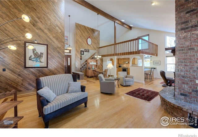 living room with beam ceiling, high vaulted ceiling, hardwood / wood-style floors, and wooden walls