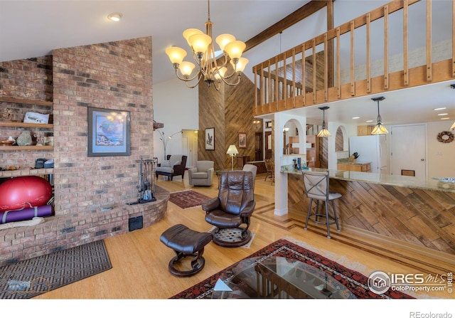 living room with a notable chandelier, wood-type flooring, and high vaulted ceiling