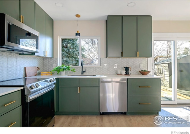 kitchen featuring pendant lighting, sink, green cabinets, and appliances with stainless steel finishes