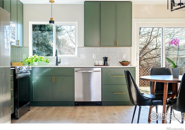 kitchen with stainless steel appliances, decorative light fixtures, and green cabinetry