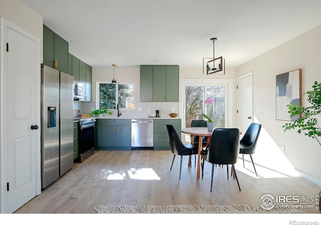 dining room featuring sink, a notable chandelier, and light hardwood / wood-style floors