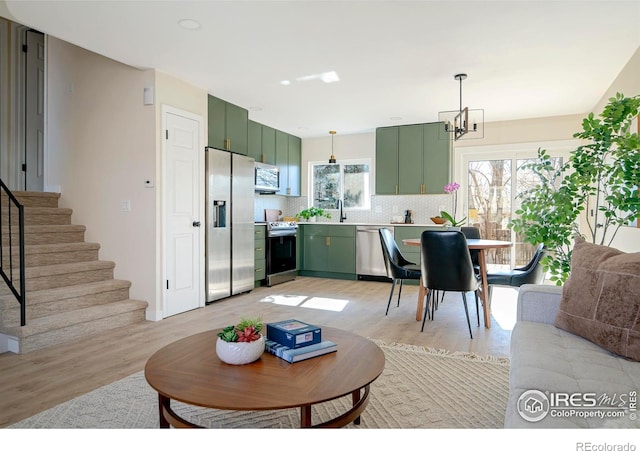 living room with a chandelier, sink, and light hardwood / wood-style flooring