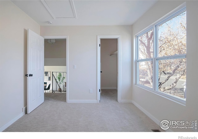 unfurnished bedroom featuring light colored carpet and a spacious closet