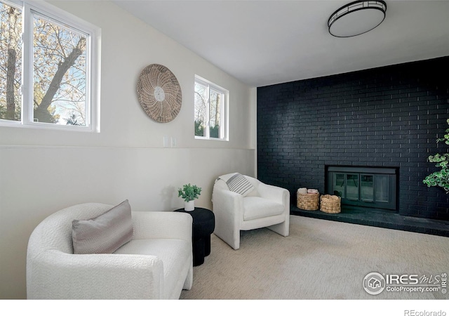 sitting room with carpet flooring and a brick fireplace