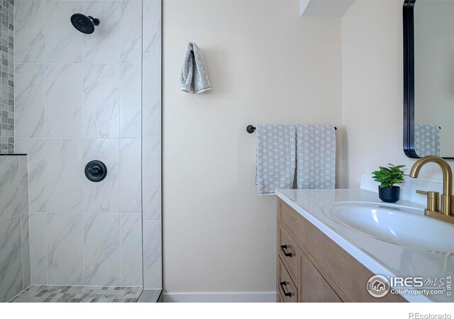 bathroom with tiled shower and vanity