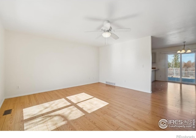 unfurnished room featuring ceiling fan with notable chandelier and hardwood / wood-style floors