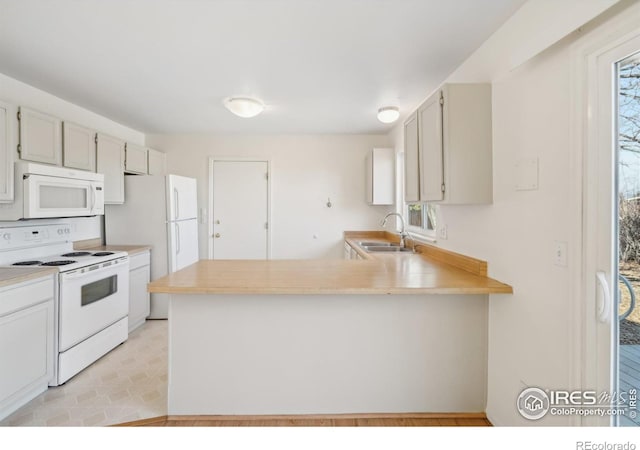 kitchen featuring white appliances, plenty of natural light, kitchen peninsula, and sink