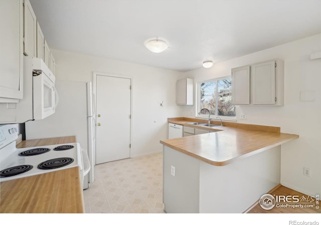 kitchen with white cabinetry, sink, white appliances, and kitchen peninsula