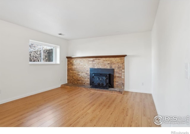 unfurnished living room featuring hardwood / wood-style flooring and a brick fireplace