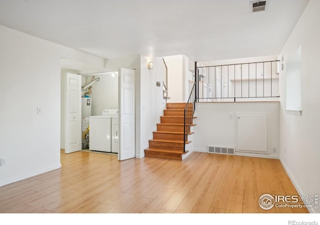 interior space with independent washer and dryer, gas water heater, and light wood-type flooring