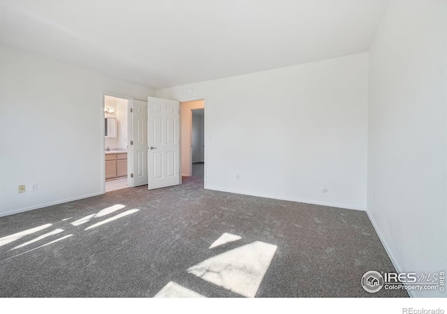 unfurnished bedroom featuring dark carpet and ensuite bath