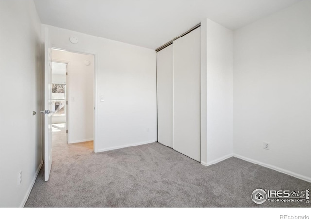 unfurnished bedroom with light colored carpet and a closet