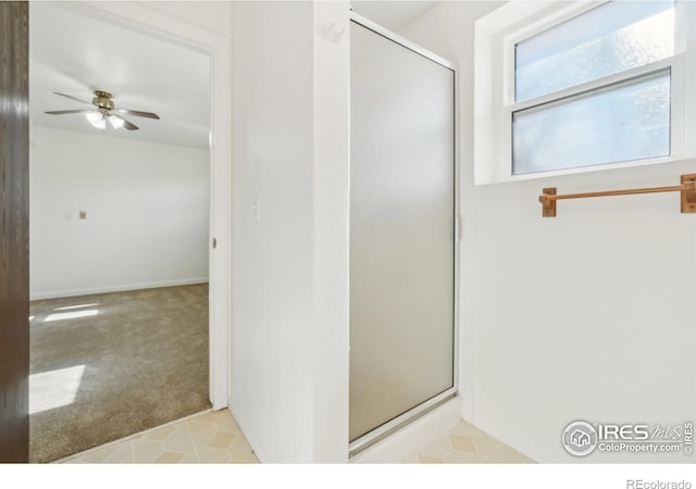 bathroom featuring a shower with shower door and ceiling fan