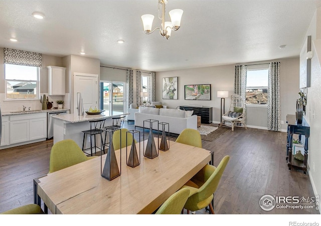 dining area with dark wood-type flooring, sink, a textured ceiling, and a notable chandelier