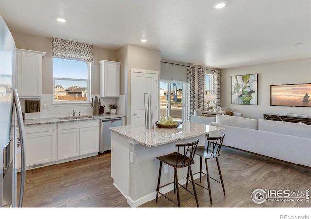 kitchen with white cabinetry, light stone counters, stainless steel appliances, and a kitchen island