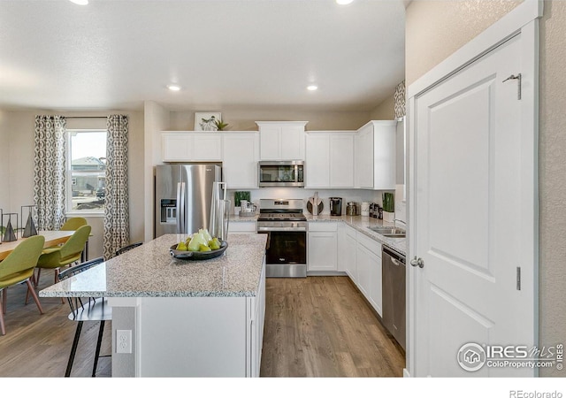 kitchen with a kitchen island, white cabinetry, a breakfast bar area, light hardwood / wood-style floors, and stainless steel appliances