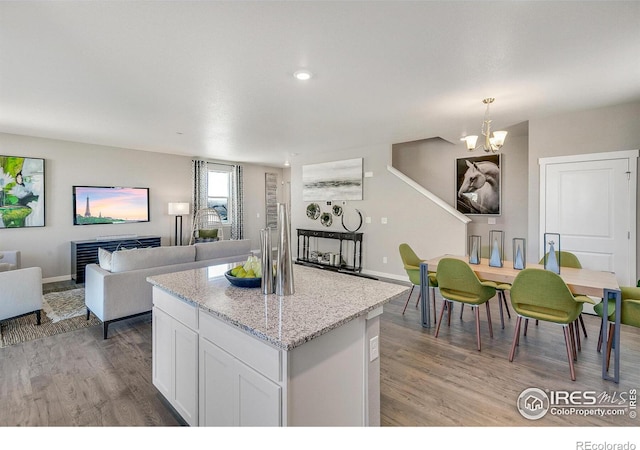 kitchen featuring decorative light fixtures, a chandelier, light wood-type flooring, light stone countertops, and white cabinets