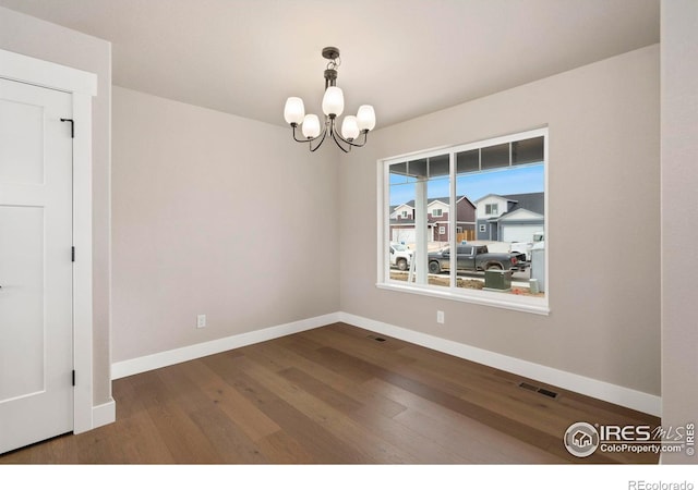 7172 Feather Reed Dr, Wellington, CO 80549 - spare room with an inviting chandelier, wood finished floors, baseboards, and visible vents