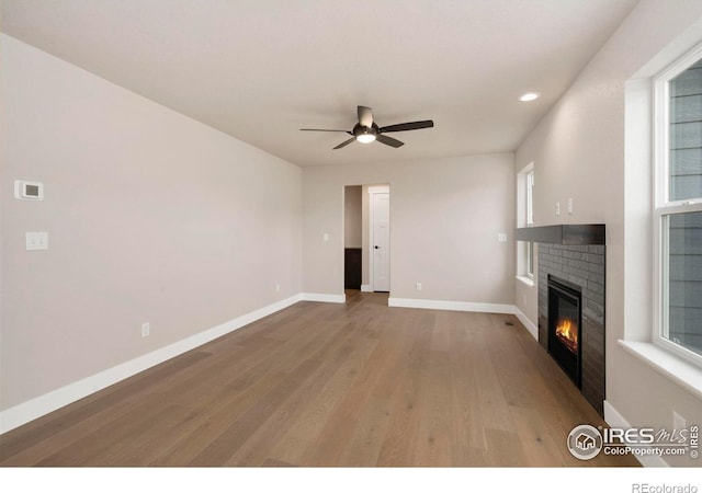 7172 Feather Reed Dr, Wellington, CO 80549 - unfurnished living room with light wood-style flooring, a brick fireplace, baseboards, ceiling fan, and recessed lighting