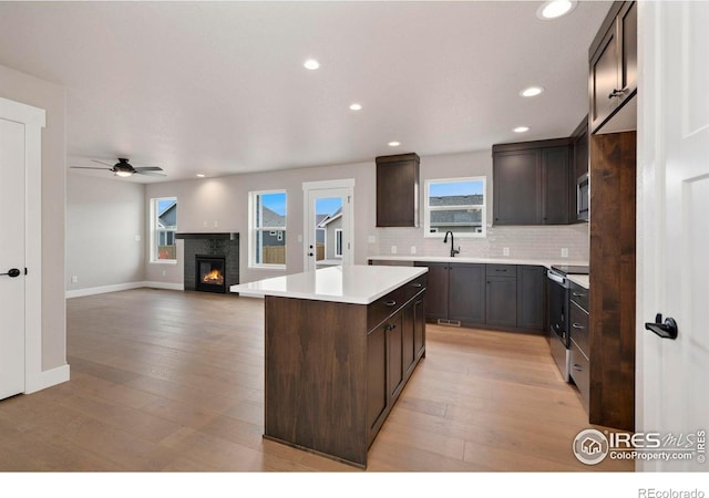 7172 Feather Reed Dr, Wellington, CO 80549 - kitchen featuring light wood finished floors, ceiling fan, stainless steel appliances, dark brown cabinets, and a kitchen island