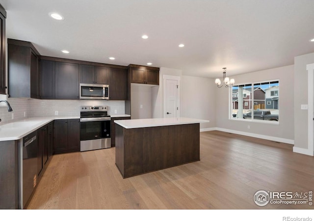 7172 Feather Reed Dr, Wellington, CO 80549 - kitchen with stainless steel appliances, decorative backsplash, a kitchen island, a sink, and a notable chandelier