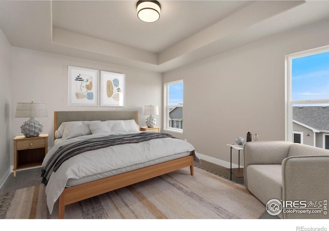 7172 Feather Reed Dr, Wellington, CO 80549 - bedroom featuring multiple windows, a raised ceiling, and baseboards