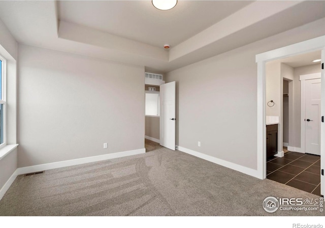7172 Feather Reed Dr, Wellington, CO 80549 - spare room with baseboards, a tray ceiling, visible vents, and dark colored carpet