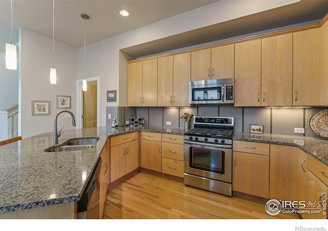 kitchen featuring pendant lighting, sink, kitchen peninsula, stainless steel appliances, and light brown cabinets