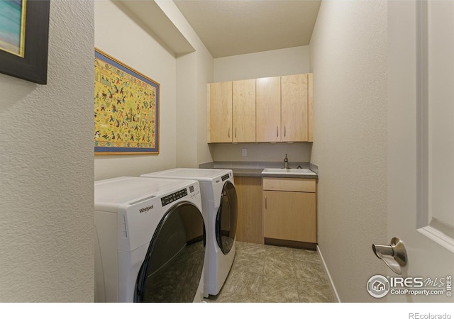 laundry area with cabinets, separate washer and dryer, and sink