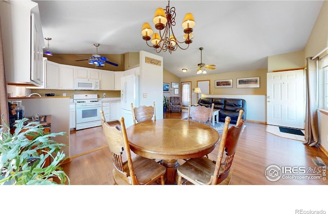 dining area featuring ceiling fan with notable chandelier, light hardwood / wood-style flooring, and vaulted ceiling