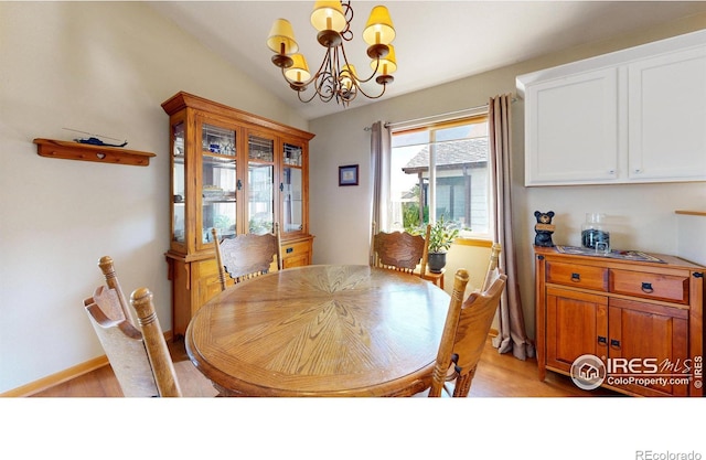 dining area with vaulted ceiling, a notable chandelier, and light hardwood / wood-style flooring