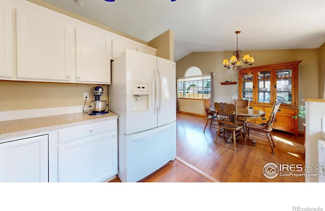 kitchen with lofted ceiling, white cabinetry, light wood-type flooring, white fridge with ice dispenser, and pendant lighting