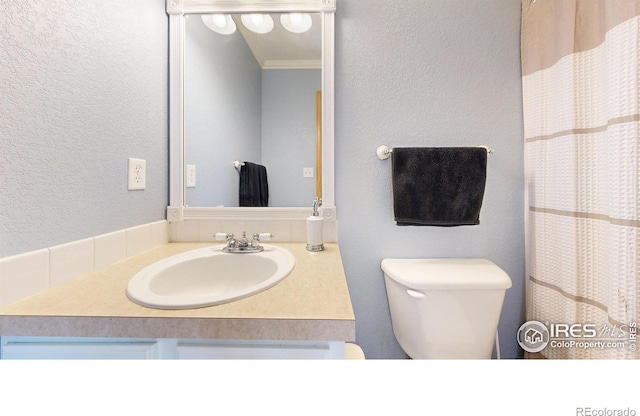 bathroom with vanity, crown molding, and toilet