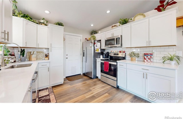 kitchen with white cabinetry, stainless steel appliances, light hardwood / wood-style floors, and sink