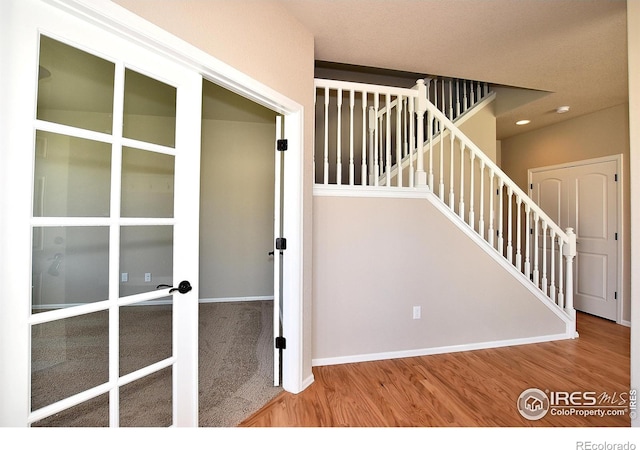 staircase with french doors and hardwood / wood-style floors