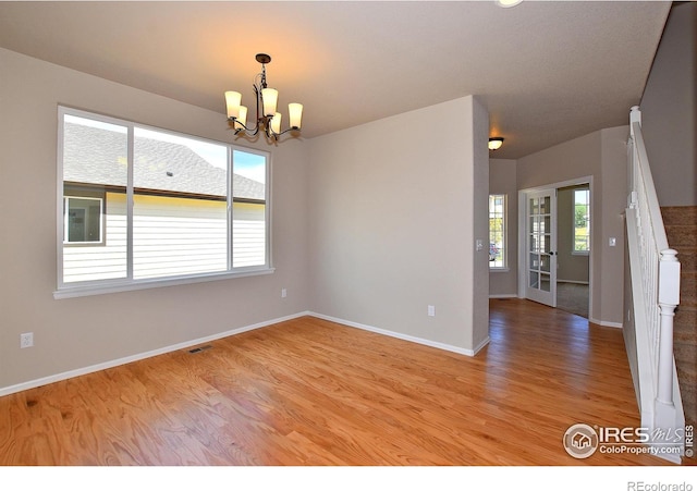 unfurnished room featuring a chandelier and light hardwood / wood-style floors