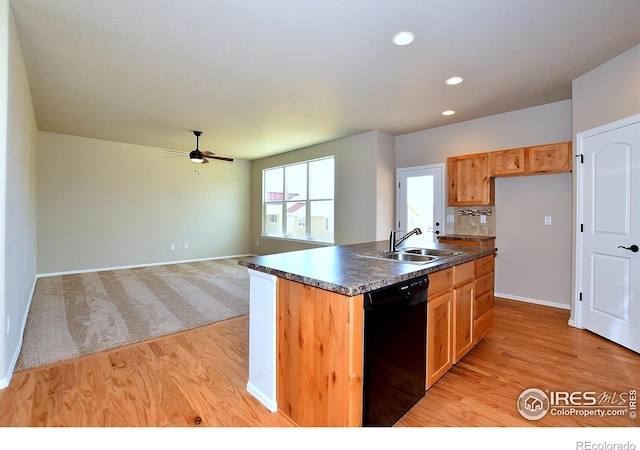 kitchen featuring sink, a kitchen island with sink, backsplash, black dishwasher, and light hardwood / wood-style floors