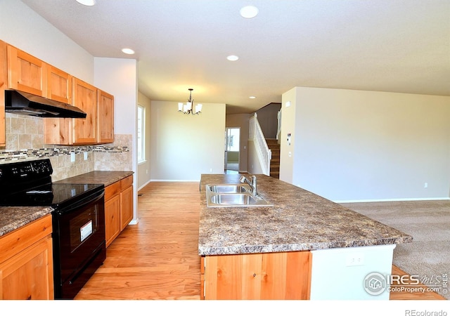 kitchen with sink, tasteful backsplash, decorative light fixtures, a center island with sink, and black / electric stove