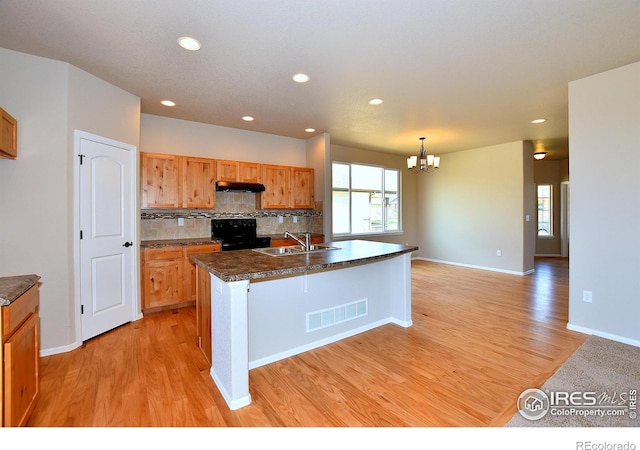 kitchen with black electric range oven, sink, light hardwood / wood-style flooring, a kitchen island with sink, and backsplash