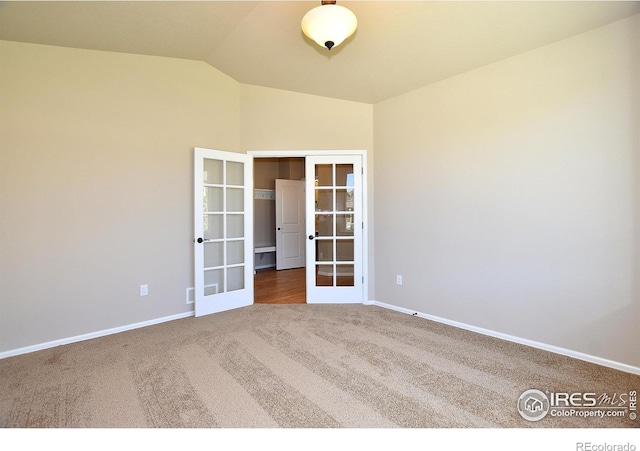 spare room featuring lofted ceiling, carpet flooring, and french doors