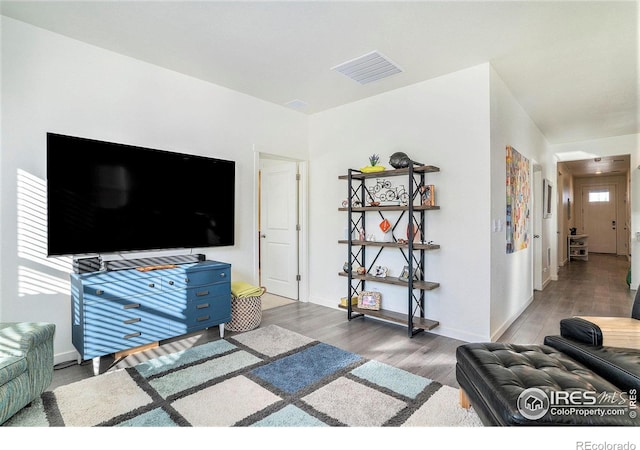 living area with visible vents, baseboards, and wood finished floors