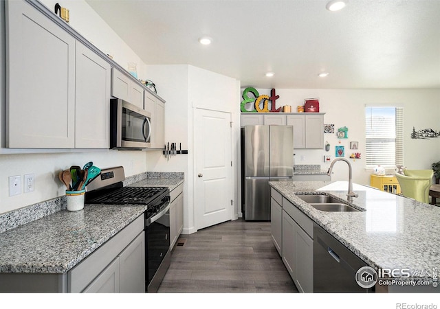 kitchen featuring a sink, light stone counters, dark wood finished floors, recessed lighting, and appliances with stainless steel finishes