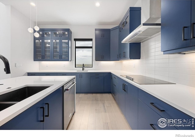 kitchen with blue cabinets, a sink, stainless steel dishwasher, wall chimney exhaust hood, and black electric stovetop