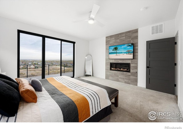 carpeted bedroom featuring visible vents, ceiling fan, and a tile fireplace