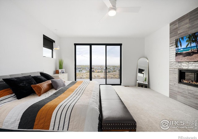 carpeted bedroom featuring access to outside, a fireplace, and ceiling fan